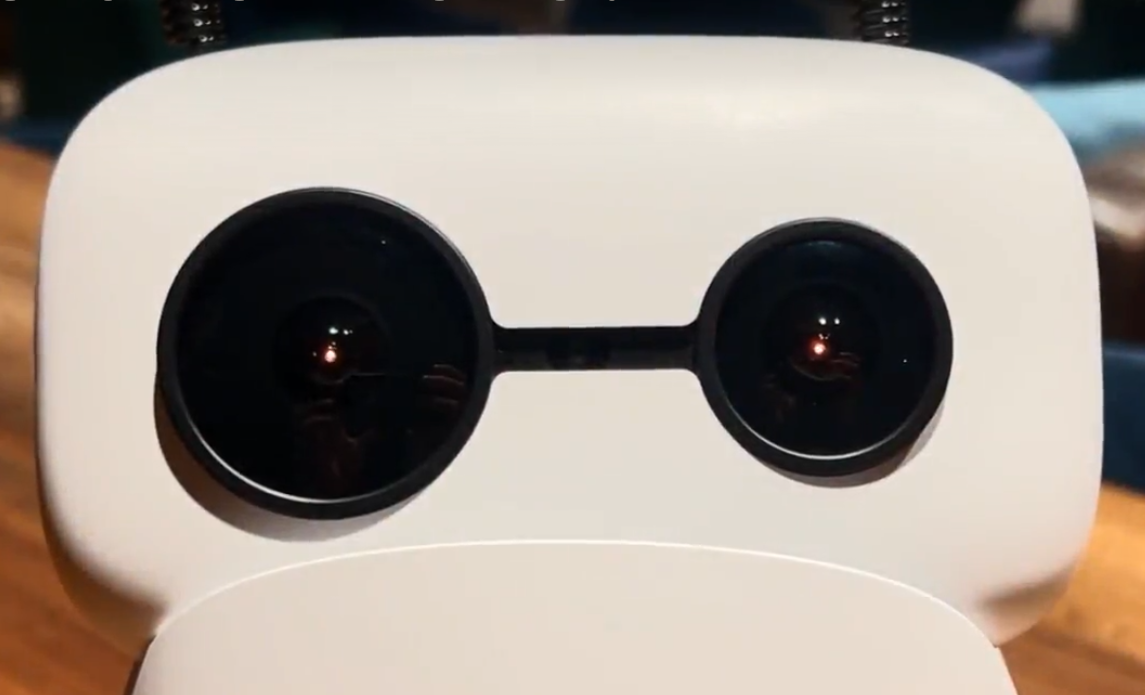 Desktop robot with glowing amber LED eyes in a workshop